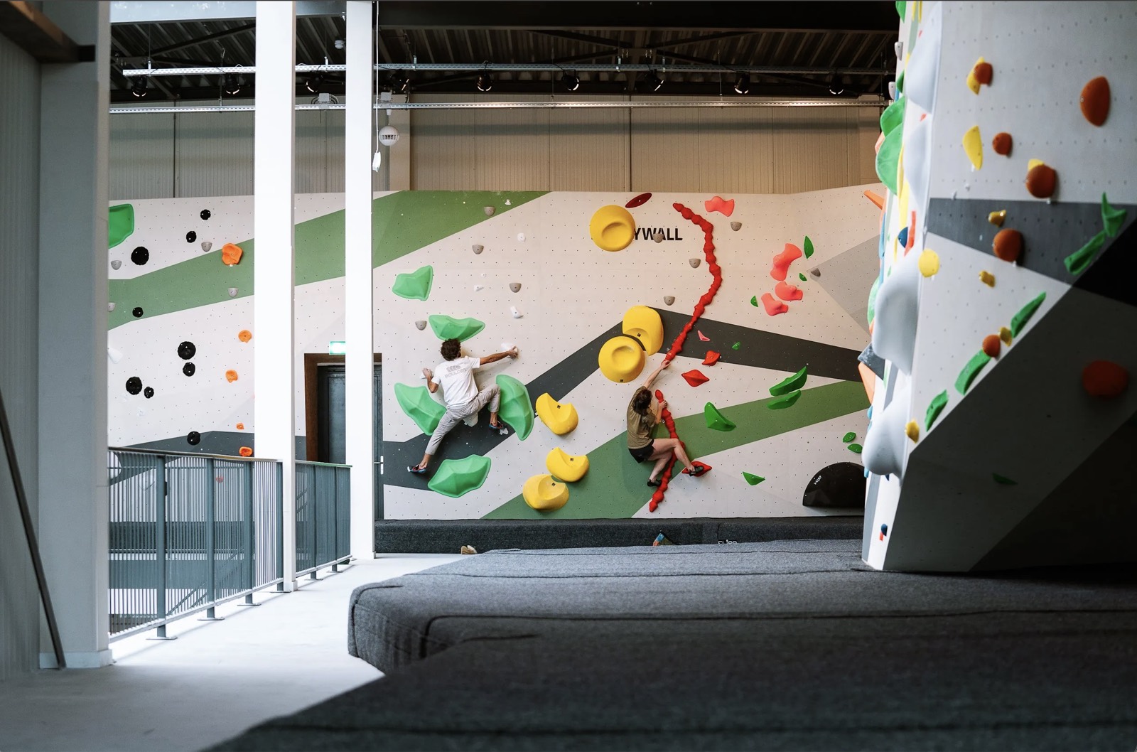 Twee boulderaars op de kleurrijke muur van een boulderhal in Eindhoven.